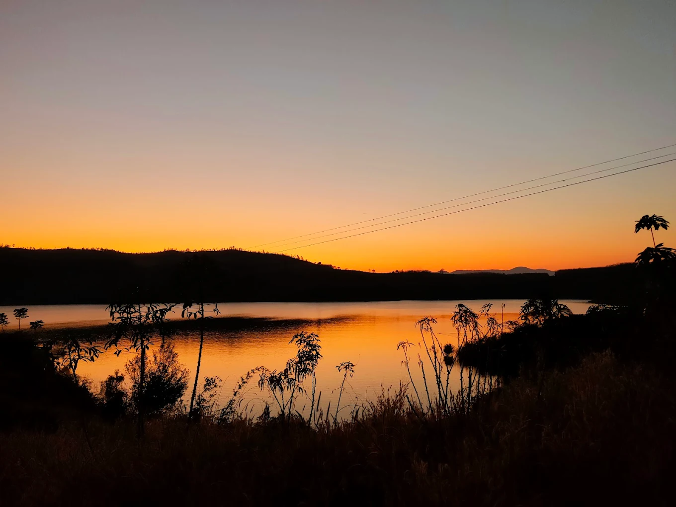 Khung cảnh hoàng hôn như tranh vẽ – sắc cam ánh tím phản chiếu mặt hồ tĩnh lặng.