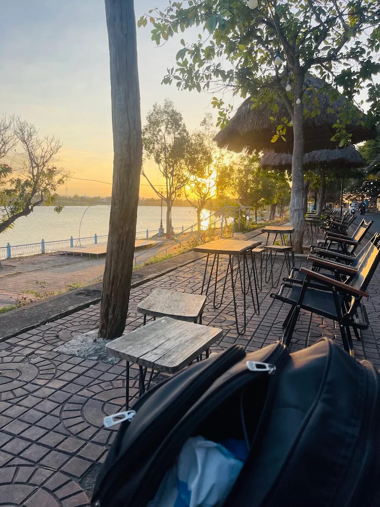 Hoàng hôn phủ nhẹ lên bàn ghế gỗ mộc bên dòng sông