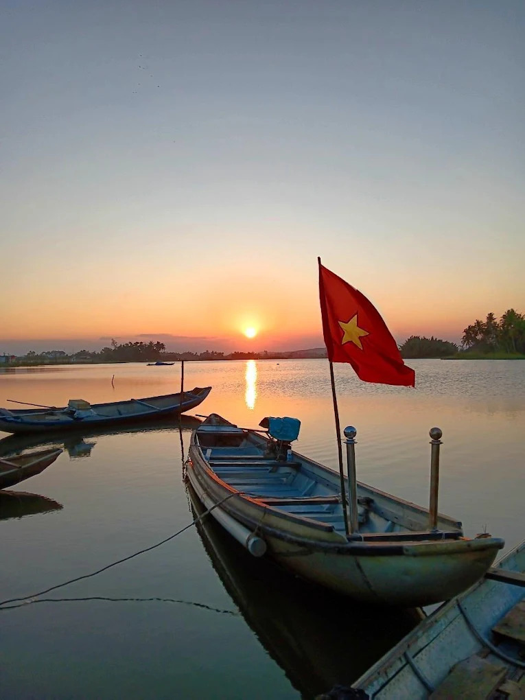 Tàu cá, mặt nước lặng và ánh hoàng hôn tạo nên khung cảnh đậm chất nghệ thuật.