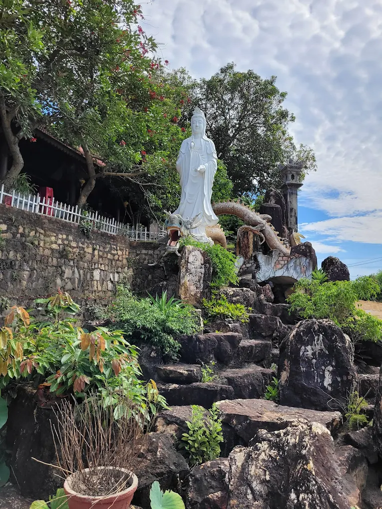 Tượng Quan Thế Âm Bồ Tát được đặt giữa khối đá và cây cổ thụ tạo nên điểm nhấn linh thiêng giữa không gian mở.