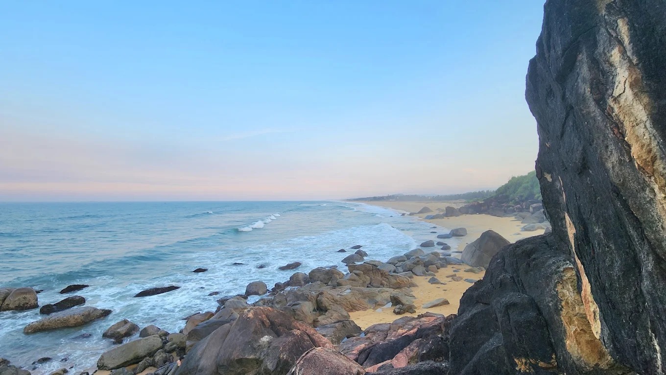 Ánh sáng buổi sáng đầu ngày nhuộm vàng cả bãi đá, sóng vỗ nhẹ vào bờ tạo nên một khung cảnh không thể rời mắt.