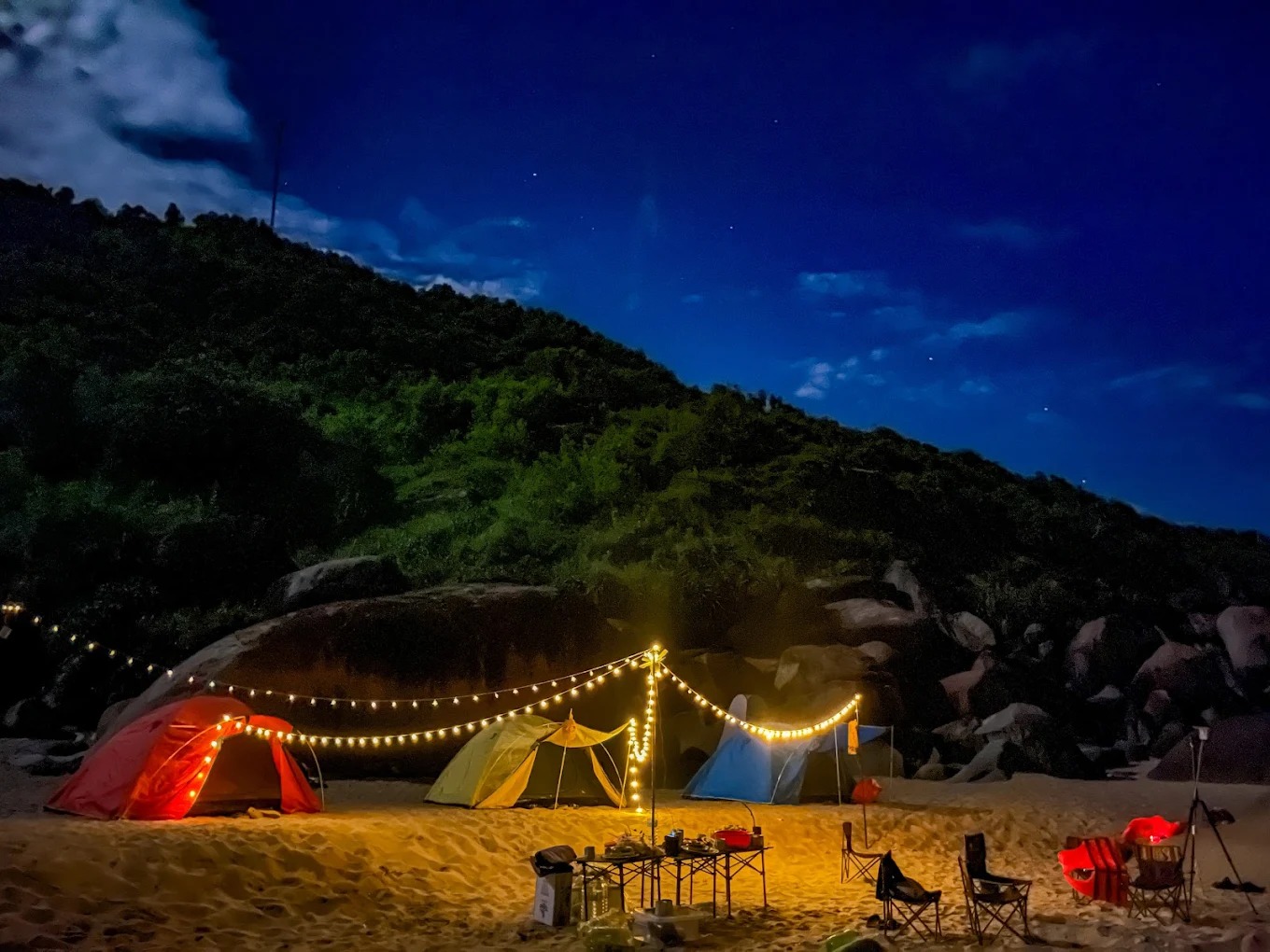 Lều đỏ, vàng nổi bật trên nền cát vàng nhạt, ánh đèn lung linh như một ngôi làng nhỏ giữa thiên nhiên hoang dã.